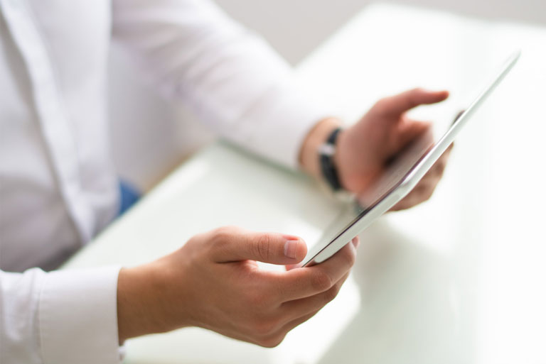 manos masculicas tomando una tablet sobre mesa blanca