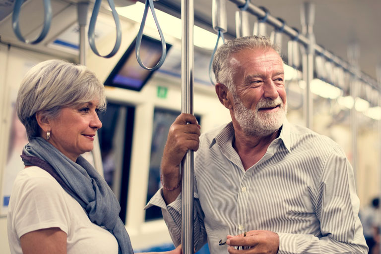 pareja de adultos mayores de pie dentro de un bagón de metro mirando hacia afuera