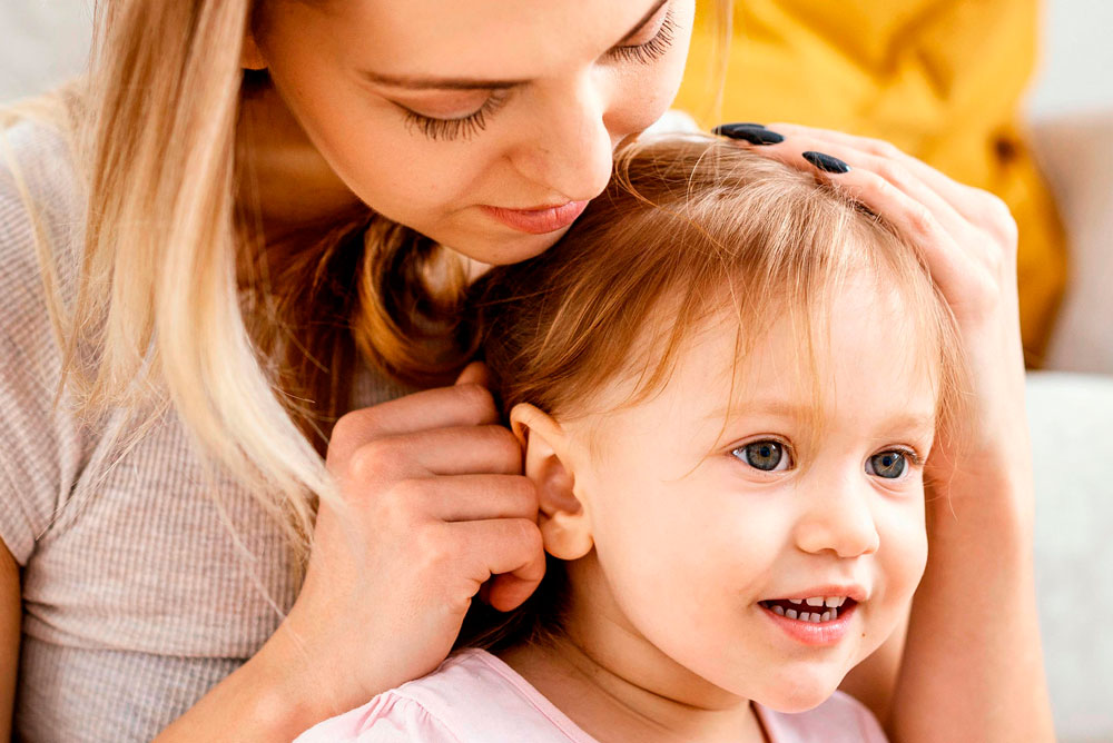 joven madre junto a su hija revisando su oido derecho